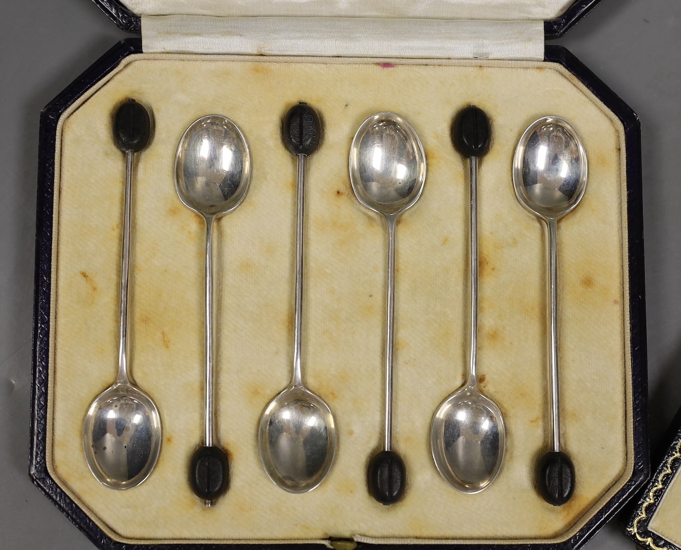 A cased set of six Elizabeth II silver and polychrome enamelled coffee spoons, Birmingham, 1960 and a cased set of six silver bean end coffee spoons.